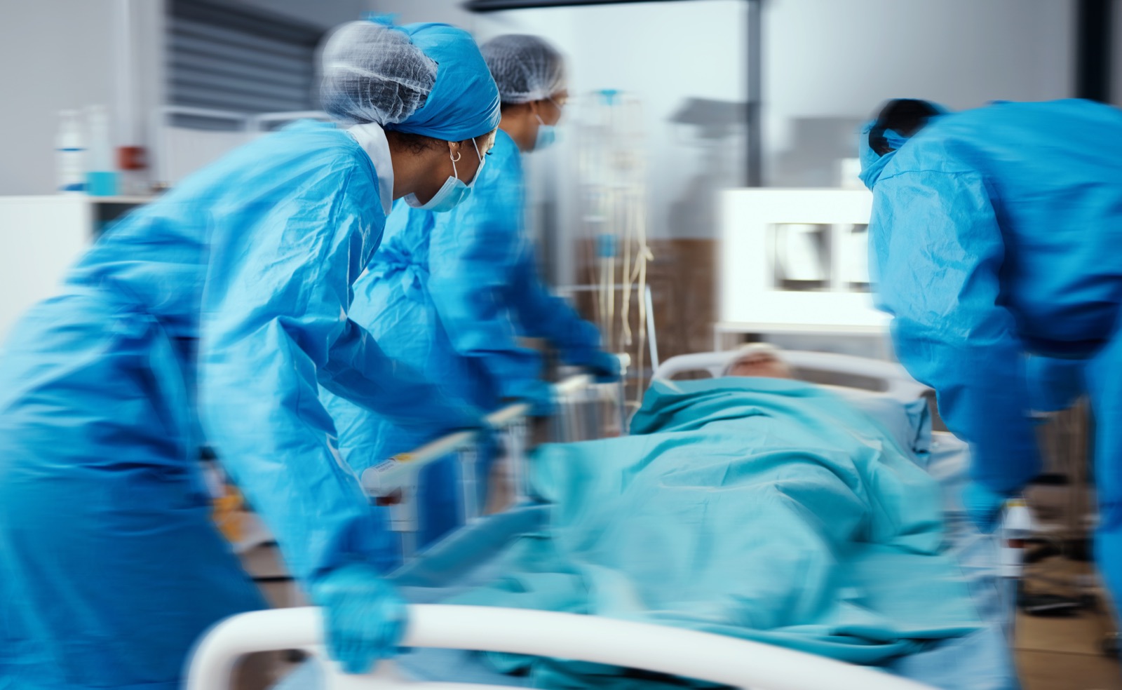 Emergency room team rushing a patient on a gurney, motion blur conveying urgency, medical staff in blue scrubs